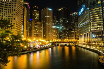 Illuminated city by river at night