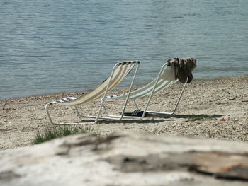 Deck chairs on sand at shore