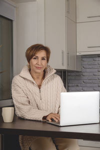 Portrait of young woman using laptop at home