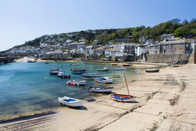 Boats moored on sea against clear blue sky