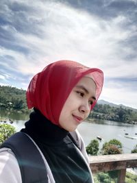 Portrait of smiling young woman standing against sky