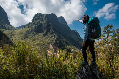 Full length of female hiker pointing at mountain