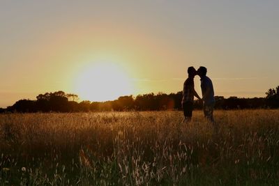 Men standing on field against sky during sunset