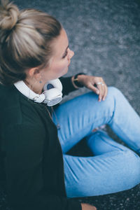 High angle view of young woman with headphones sitting on road