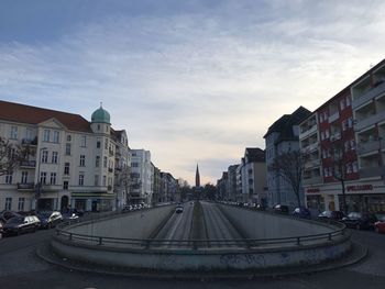 Street amidst buildings against sky during sunset