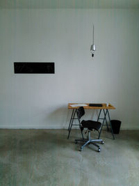 Empty chair and table against wall at home