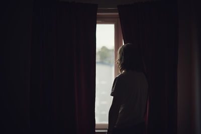 Silhouette of person looking through window