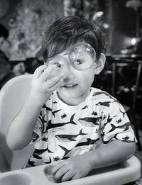 Close-up of boy touching bubble while sitting on high chair at home