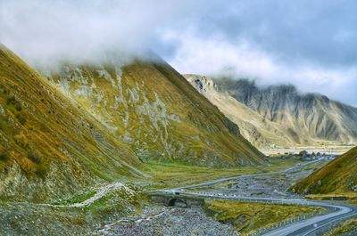 Scenic view of road by mountains against sky