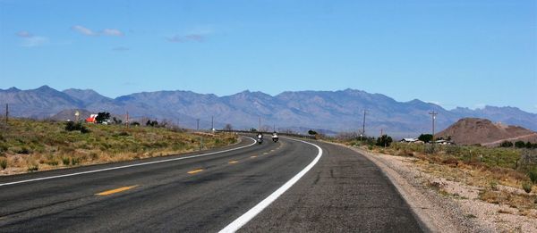 Road by mountains against clear sky