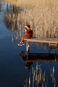 Woman with arms outstretched standing on lake