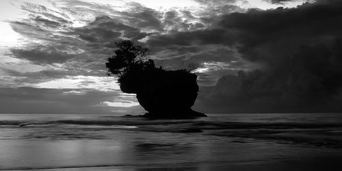 Silhouette rock in sea against sky