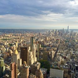 High angle view of city buildings against cloudy sky