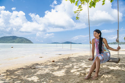 Beautiful woman sitting on a swing at the beach in phuket