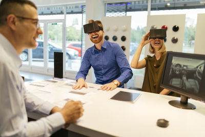 Couple using vr glasses in car dealership