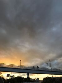 Silhouette suspension bridge over sea against sky during sunset