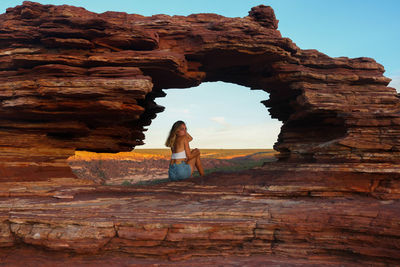 Young woman at natural red rock window with spectacular views in kalbarri national park in australia