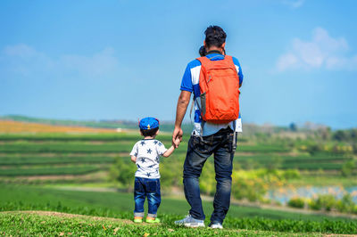 Rear view of father and son standing on field