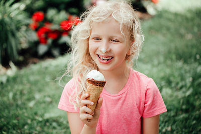  funny adorable girl with dirty nose and milk moustaches eating licking ice cream from waffle cone. 