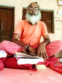 Bearded man in traditional clothing reading book at home