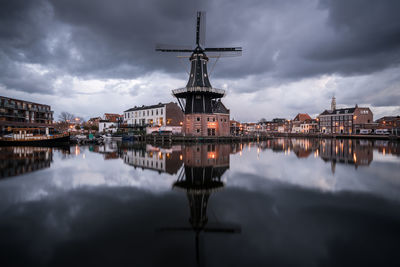 Reflection of traditional windmill in city against sky