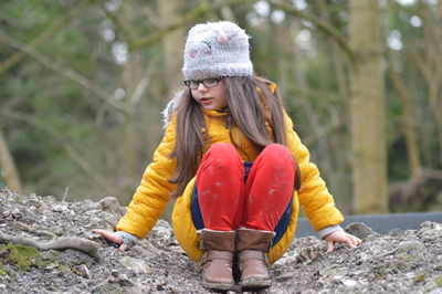 Cute girl sitting on dirt road during winter