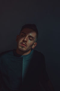 Portrait of man standing against black background
