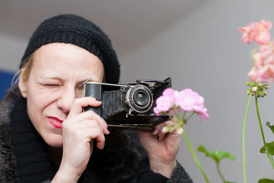 Close-up of woman photographing pink flowers with vintage camera