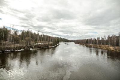 View of lake in forest against cloudy sky