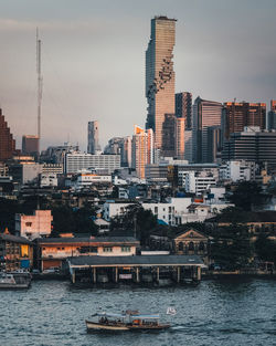 River by modern buildings against sky in city