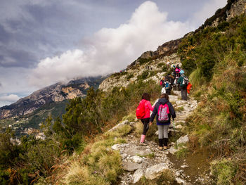 Rear view of people walking on mountain against sky