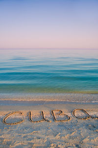 Cuba text on sea shore against clear sky