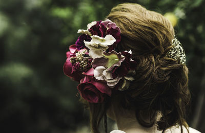 Close-up of woman wearing flowers against plants