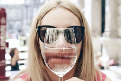 Close-up portrait of woman covering face with wineglass outdoors