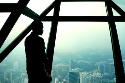 Silhouette of buildings against sky seen through glass window