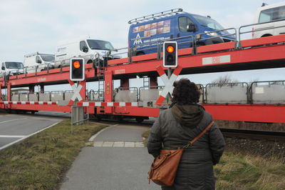 Rear view of man standing on train against sky