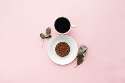 Woman international day concept, coffee cup, plate, cookie, branch, leaves on pink background
