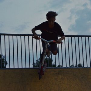 Full length of man standing on railing against sky