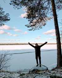 Full length of person standing at riverbank against sky