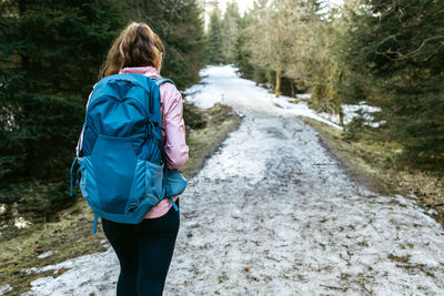 A young girl goes hiking in the early spring in the forest. the girl walks with a backpack 