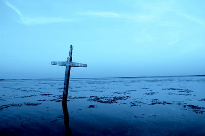 View of cross on sea against blue sky