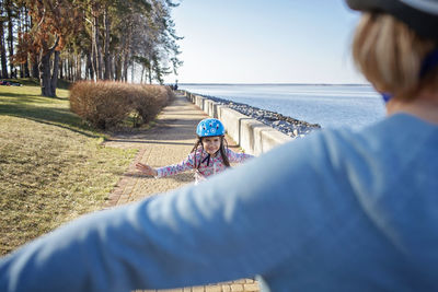 Rear view of grandmother with granddaughter against sky