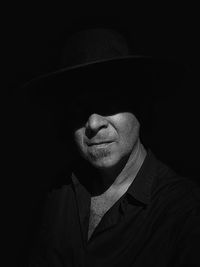 Portrait of man wearing hat against black background