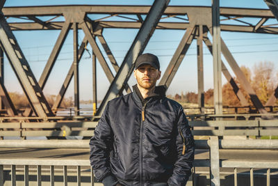 Portrait of young man standing against railing