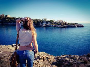 Portrait of young woman standing on rock against lake