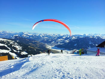 Person paragliding on snow covered landscape against sky