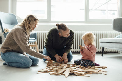 Cute girl playing jenga with parents at home