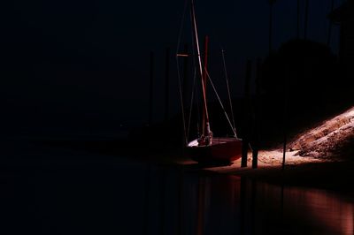 Sailboat moored at sea shore during night