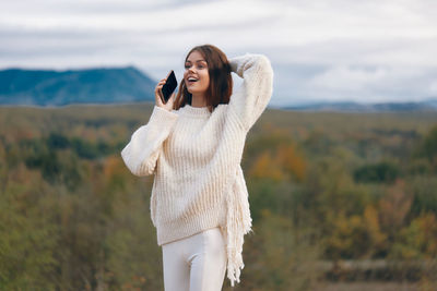 Portrait of young woman standing against mountain