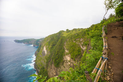 Scenic view of sea by mountain against sky